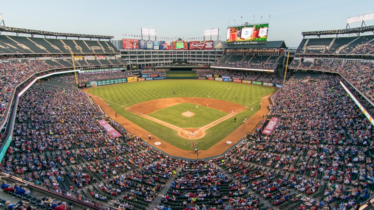 A packed baseball stadium with fans watching a game from the stands.